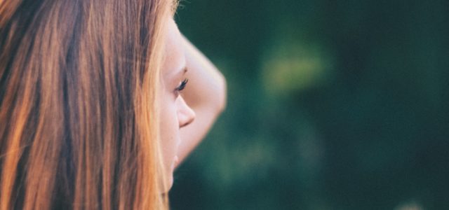 Young woman holds her hair back while she thinks about the pain and marginalizing of stigma.